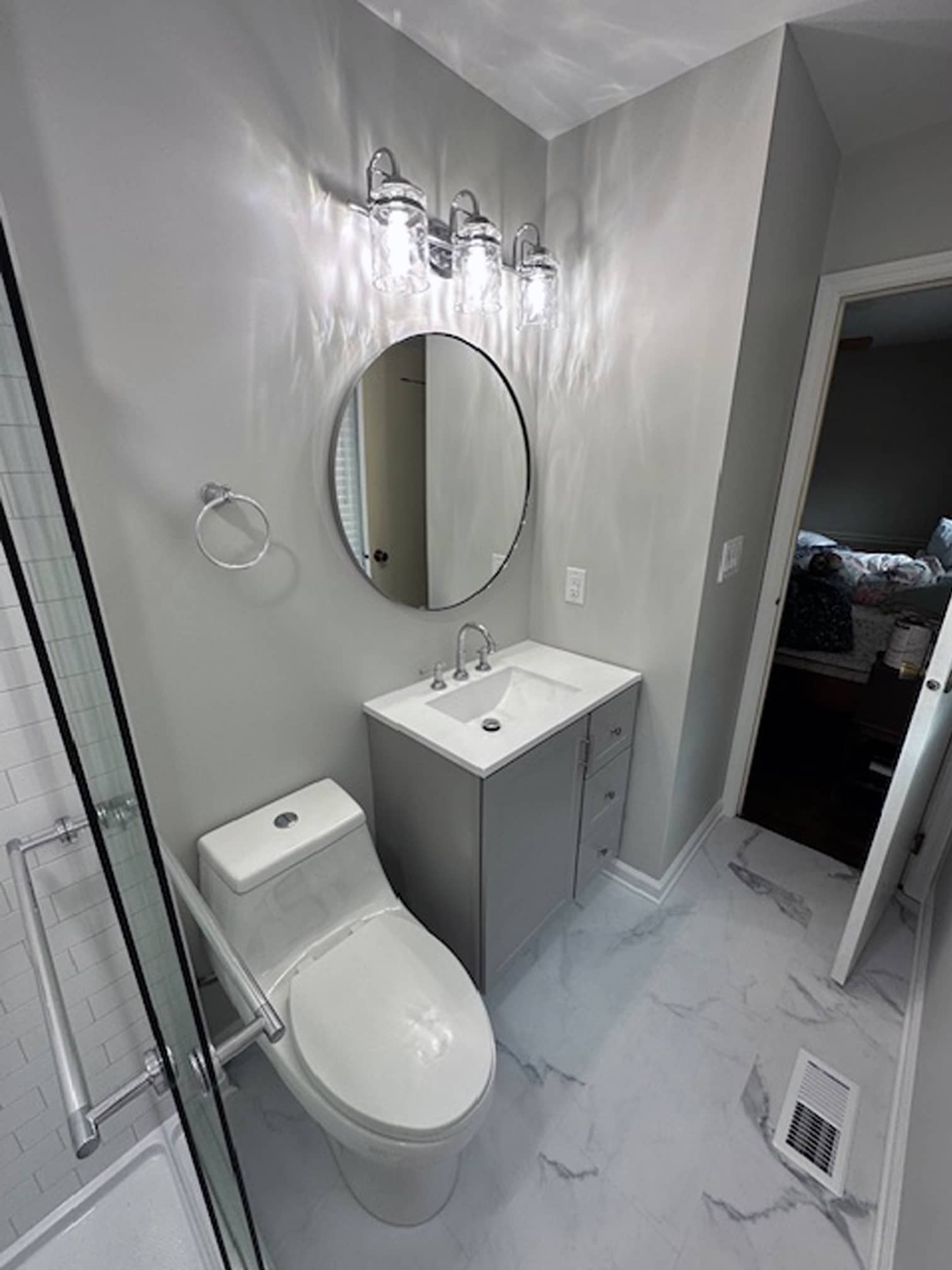 Contemporary bathroom with round mirror and clean white finishes in Powell, OH