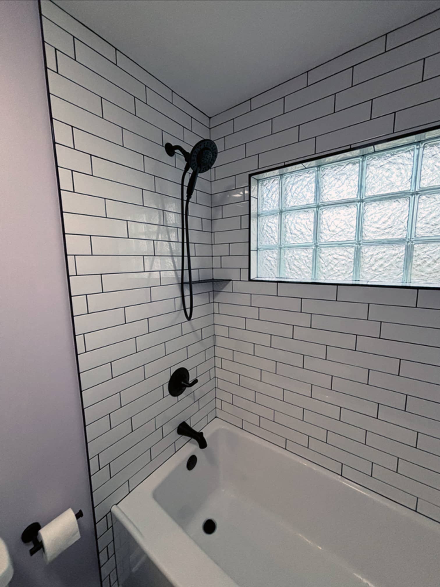 Bathtub and shower combo with white subway tile and black fixtures in a Westerville, OH home renovation
