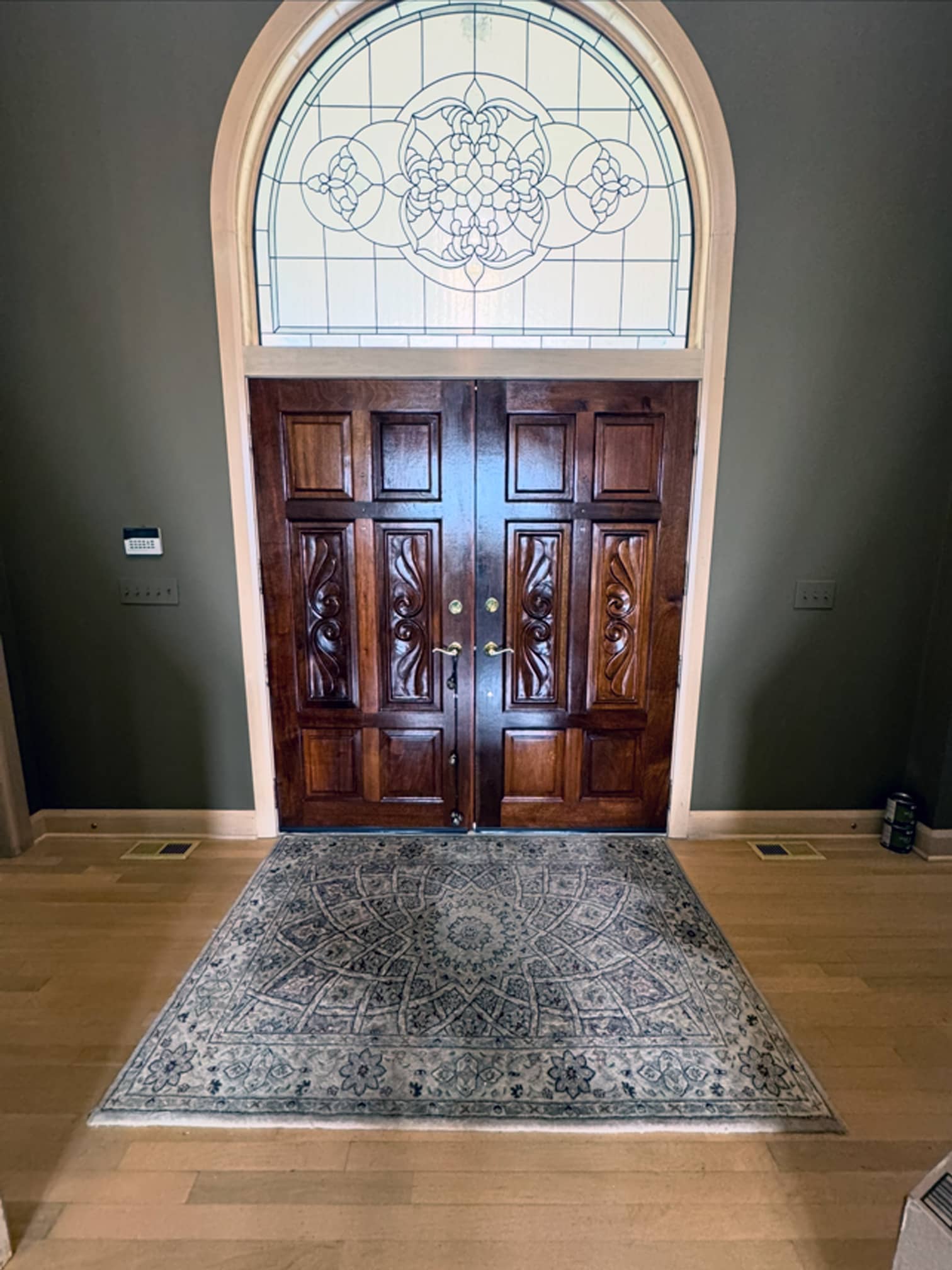 Entryway with tall wooden front door and arched window in a Grove City, OH home